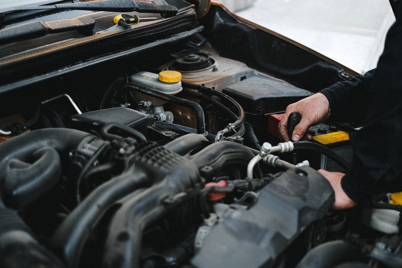 Close-up of a mechanics hands working on a car engine, showcasing repair work.